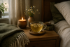 A glass of chamomile tea on a bedside table beside a candle
