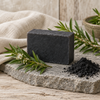 Charcoal and tea tree soap bar on a slate slab with tea tree sprigs